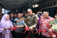 Tri Adhianto memotong pita merah saat meresmikan hasil pembangunan program Rumah Tidak Layak Huni di Kecamatan Pondok Gede